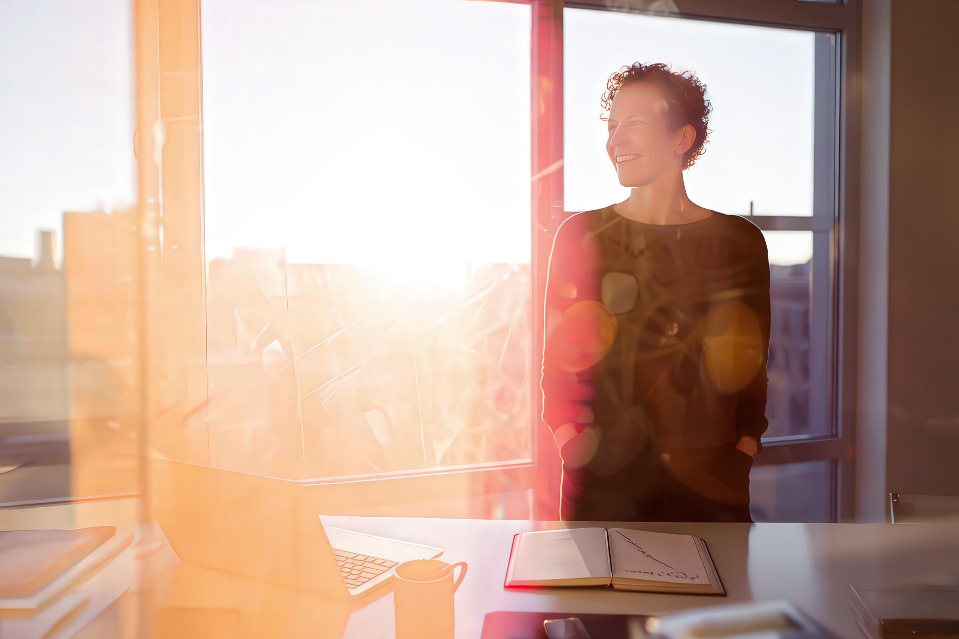Social media manager standing by an office window at dusk, with data reflections and city lights