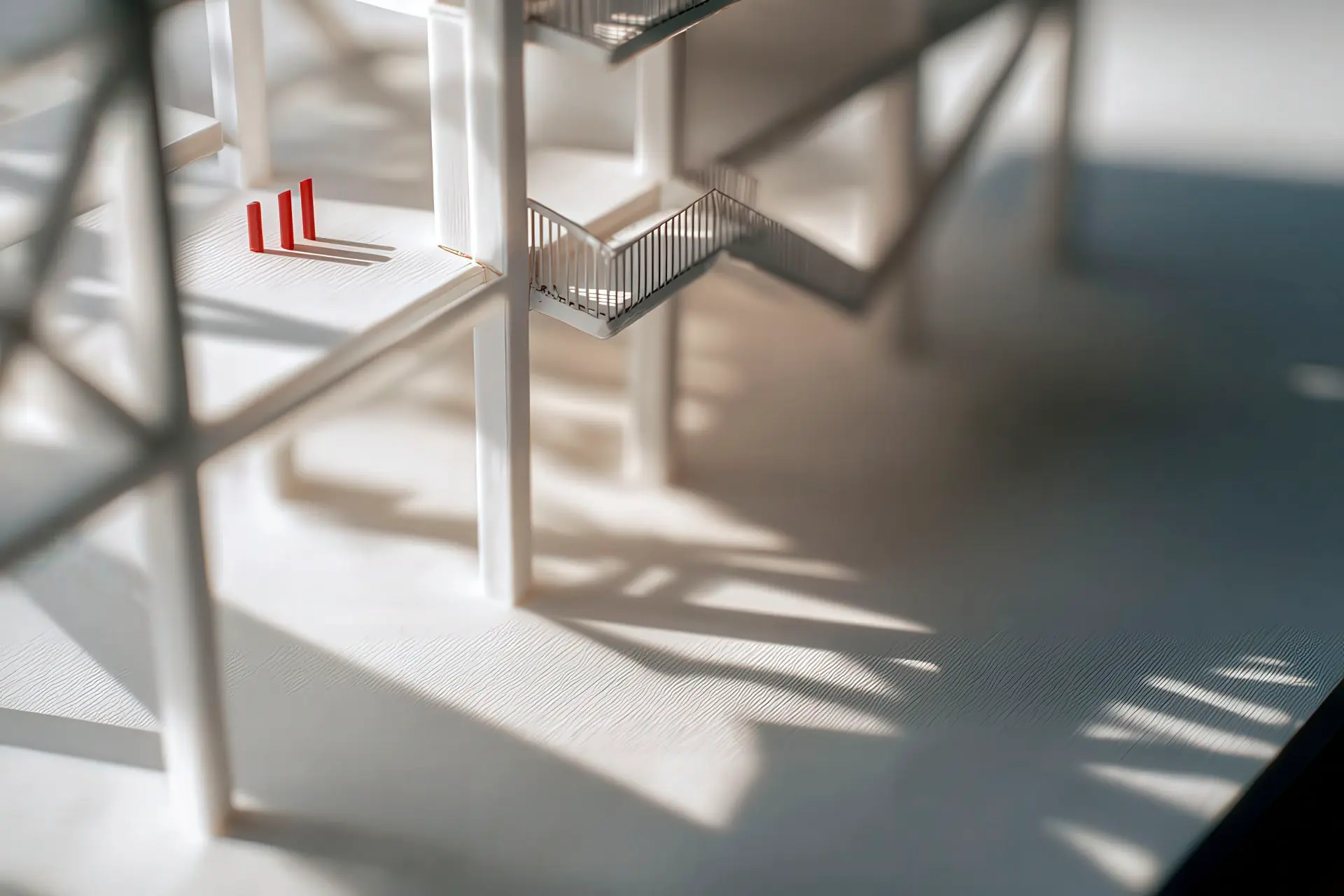 White architectural model with a red structural accent in #da291c